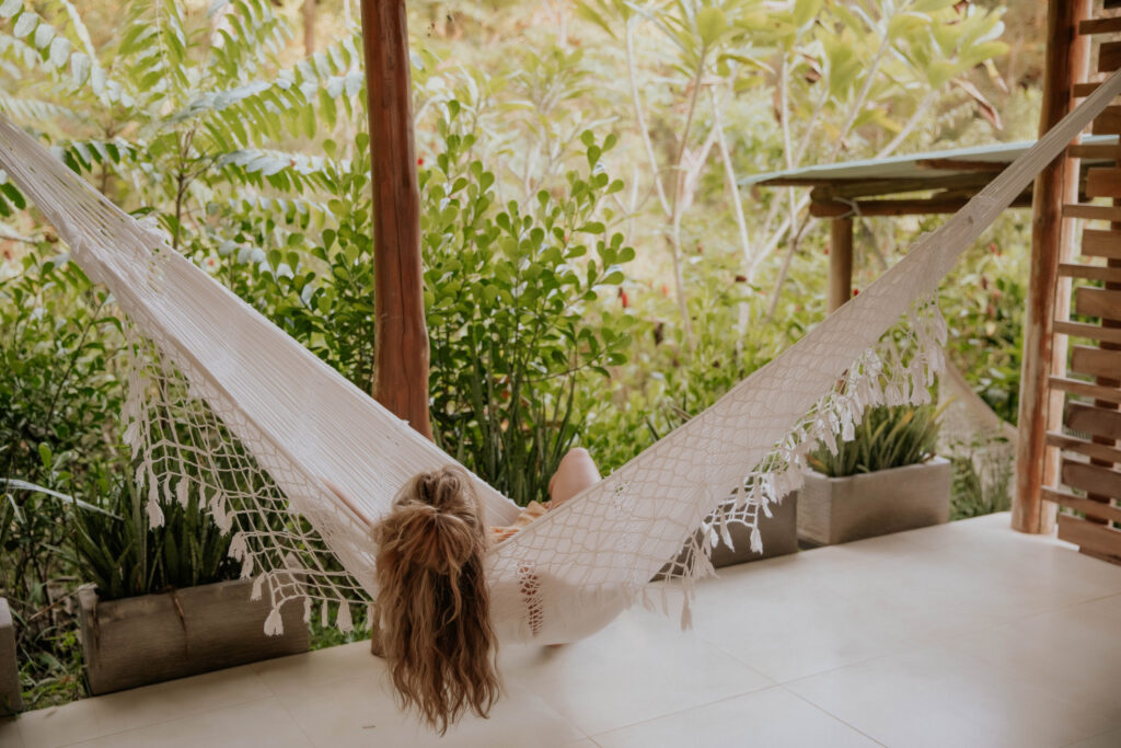 A guest resting in a handwoven hammock on a private bungalow terrace, framed by the tropical jungle at Hacienda del Sol in Guanacaste, Costa Rica.