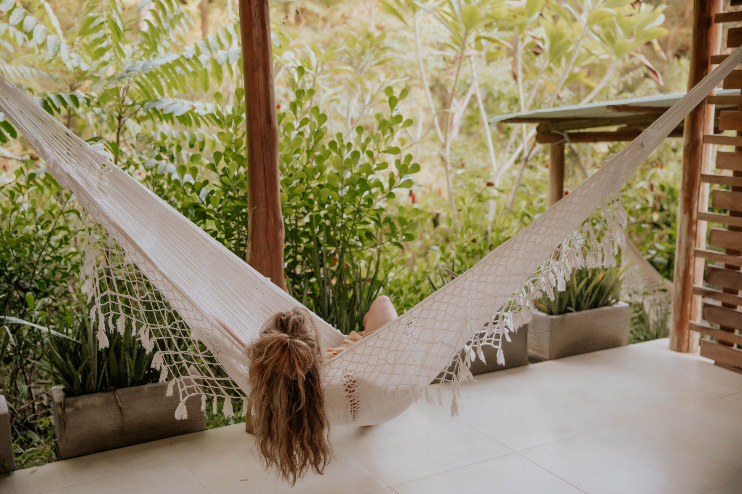 A guest resting in a handwoven hammock on a private bungalow terrace, framed by the tropical jungle at Hacienda del Sol in Guanacaste, Costa Rica.